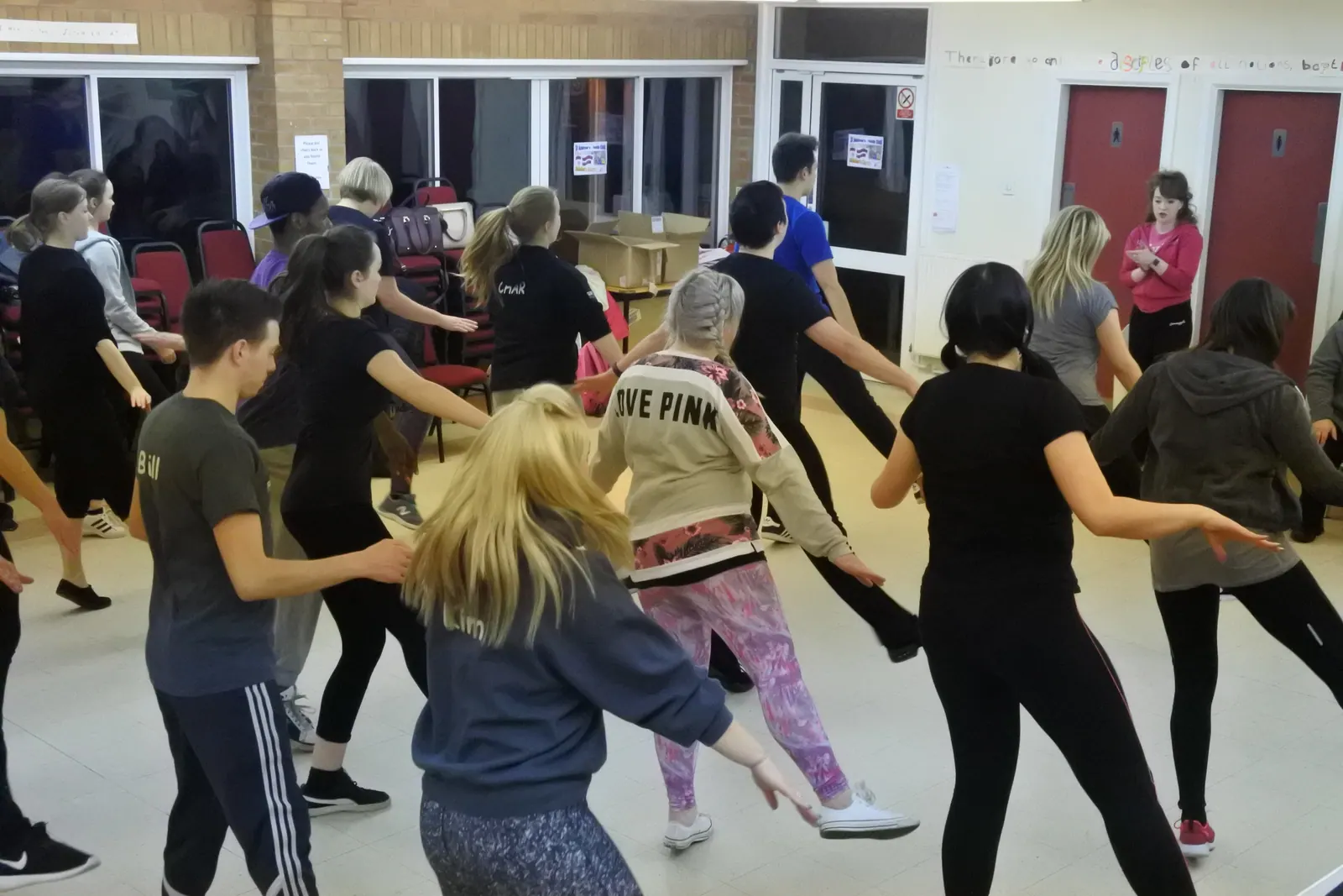 The whole room caught mid-turn, mostly backs and shoulders, everybody moving at once.