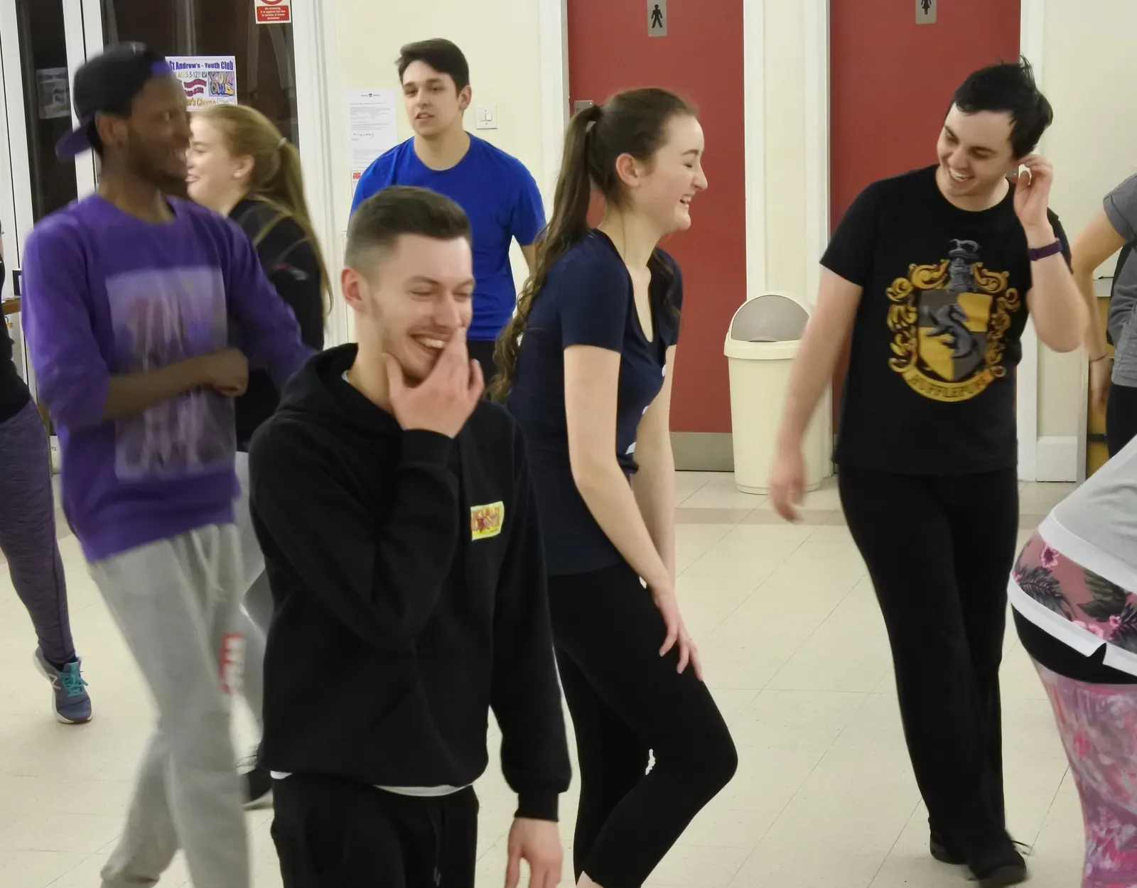 Five members standing together and laughing part way through a number.